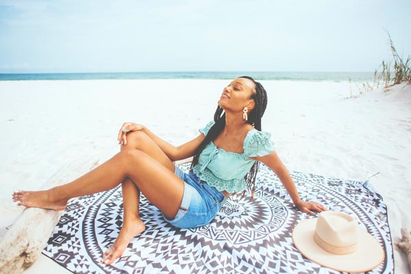 Woman at the beach sitting on Tesalate Beach Towel